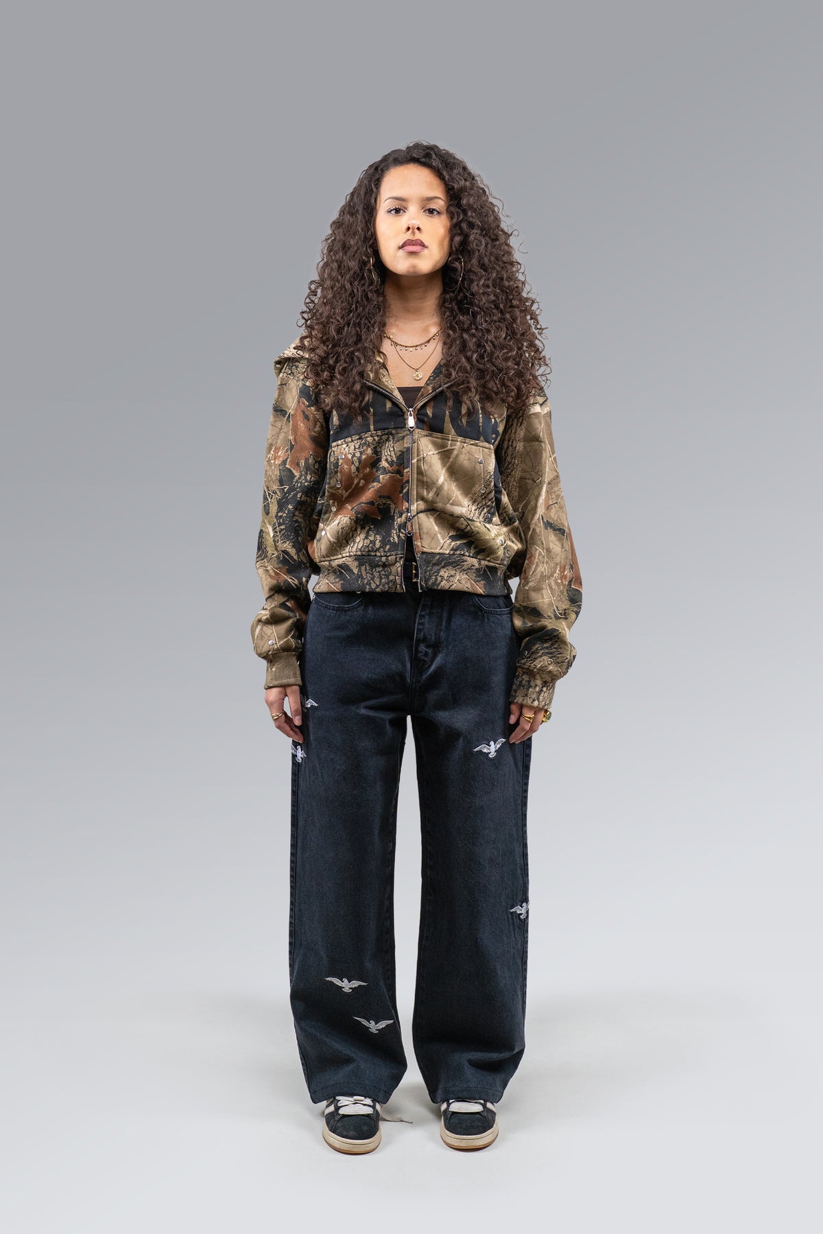 Female model wearing Redemption Camo Zip Hoodie and Redemption Jeans, front view